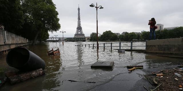 A woman takes photos of the flooded banks of the Seine river in Paris, France Saturday June 4, 2016. The level of the Seine started to drop after peaking earlier in the morning. Both the Louvre and Orsay museums were closed as officials said the Seine had been at its highest level in nearly 35 years. (AP Photo/Francois Mori)