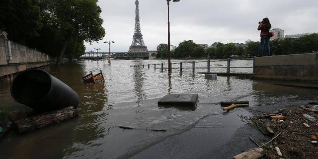 A woman takes photos of the flooded banks of the Seine river in Paris, France Saturday June 4, 2016. The level of the Seine started to drop after peaking earlier in the morning. Both the Louvre and Orsay museums were closed as officials said the Seine had been at its highest level in nearly 35 years. (AP Photo/Francois Mori)
