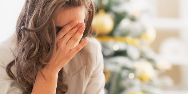 Stressed young woman in front of christmas tree