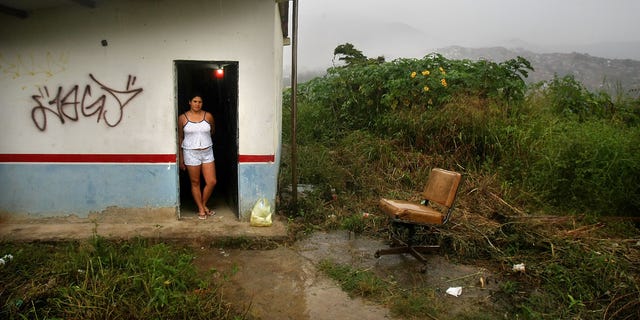 Carolina Olivera stands in her front door in the poor barrio of Petare in Caracas, Venezuela.
