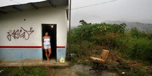 Carolina Olivera stands in her front door in the poor barrio of Petare in Caracas, Venezuela.