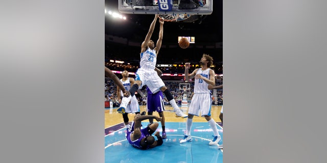 New Orleans Hornets power forward Anthony Davis (23) dunks over Sacramento Kings center DeMarcus Cousins, on the court, during the first half of an NBA basketball game in New Orleans, Sunday, Feb. 24, 2013. At right is Hornets center Robin Lopez (15). (AP Photo/Gerald Herbert)