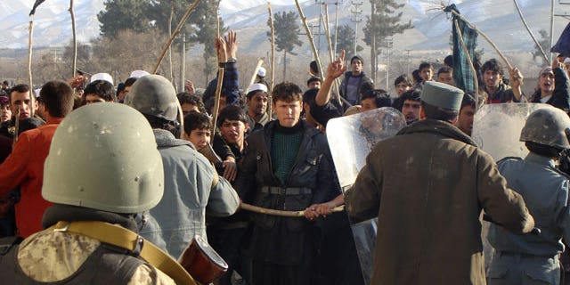 Feb. 24, 2012: Afghan police tries to restrain demonstrators during an anti-US protest in Baghlan province, north of Kabul, Afghanistan.