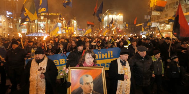 A Ukrainian nationalist carries a portrait of Stepan Bandera, founder of the Ukrainian rebel army that fought against the Soviet regime, during a rally in downtown Kiev, Ukraine, late Wednesday, Jan. 1, 2014. The rally was organized on the occasion of Bandera's birth anniversary.(AP Photo/Efrem Lukatsky)