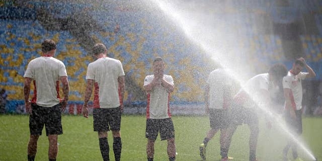 Steven Defour, center, of the Belgium soccer team wipes his face from the spray of a sprinkler at a training session at the Maracana Stadium in Rio de Janeiro, Brazil, Saturday, June 21, 2014. Belgium play in group H of the 2014 soccer World Cup.(AP Photo/Wong Maye-E)