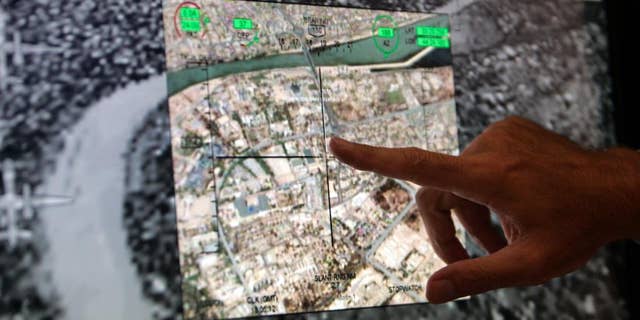FILE -This July 17, 2008 file photo shows Mark Bigham, director of business development for US Raytheon Tactical Intelligence Systems, pointing to downtown Baghdad, Iraq, on a screen of the newly-unveiled control system for unmanned drones at the Farnborough aerospace show, in Farnborough, England. A Pentagon official says the U.S. has started flying armed drones over Baghdad to protect U.S. civilians and military forces in the Iraqi capital. The official said the flights started in the last 24 to 48 hours to bolster manned and unmanned reconnaissance flights the military has been sending over violence-wracked Iraq in recent weeks. He spoke on condition of anonymity because he was not authorized to discuss the new flights on the record. (AP Photo/Lefteris Pitarakis, File)