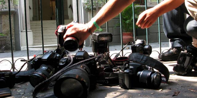 FILE - In this April 29, 2012, file photo, photojournalists place their cameras on the ground during a demonstration in Mexico City condemning the alleged murder of fellow journalist Regina Martinez, a correspondent for the Mexican investigative magazine Proceso. Ruben Espinosa, a photographer who worked for Proceso and other media, was among five people found slain early Saturday, Aug. 1, 2015, in an apartment in Mexico City, according to the magazine. He had recently gone into self-exile from the Gulf coast state of Veracruz, where he felt under threat, the magazine added. According to the Committee to Protect Journalists, 11 journalists have been killed in Veracuz since 2010, the most recent just a month ago. Two others, including Espinosa, were Veracruz journalists found dead outside of the state. (AP Photo/Marco Ugarte, File)