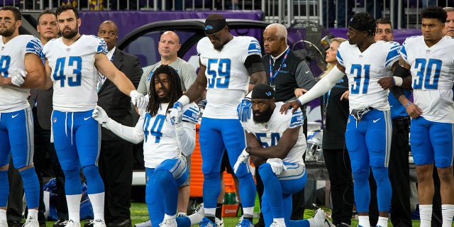 Detroit Lions players kneel while others stand during the national anthem before the game against the Minnesota Vikings.