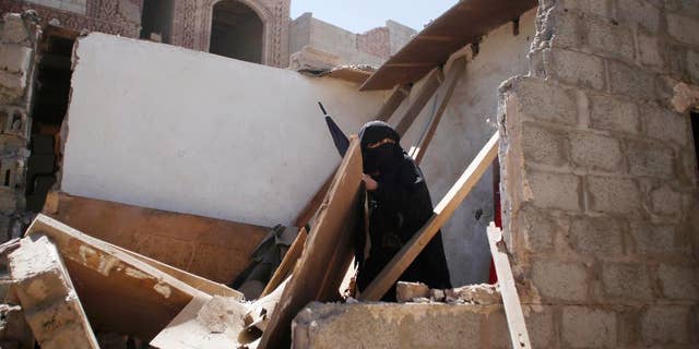 A woman stands on her house destroyed by Saudi-led airstrikes in Sanaa, Yemen, Friday, May 1, 2015. Saudi Arabia leads a coalition of mostly Sunni Arab countries conducting airstrikes against the rebels who have overrun the Yemeni capital, Sanaa, and forced the Western-backed president, Abed Rabbo Mansour Hadi, to flee the country. (AP Photo/Hani Mohammed)