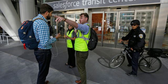 FILE: Mike Eshleman, with AC Transit, directs people away from the Salesforce Transit Center following its closure.