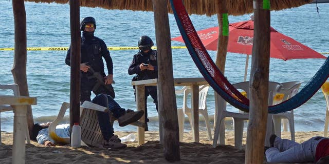 FILE - In this Jan. 6, 2017 file photo, state police inspect the site where two men were shot at the Tamarindos beach in the port city of Acapulco, Mexico. Mexico has surpassed 2,000 murders in a month for the first time since the summer of 2011, and had more murders in the first quarter of 2017 than in the start of any year in at least two decades, according to data released Friday, April 20, 2017. (AP Photo/Bernandino Hernandez, File)
