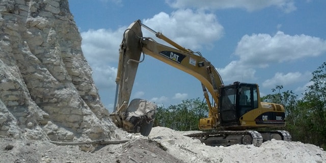 En esta foto tomada por Jaime Awe, director del Instituto de ArqueologÃa de Belice, se ve una retroexcavadora extrayendo piedras de una de las pirámides mayas más grandes de Belice, el 10 de mayo de 2013. Las autoridades denunciaron que una compañÃa constructora prácticamente destruyó una pirámide para extraer piedras destinadas a un proyecto de construcción de caminos. (Foto AP/Jaime Awe)