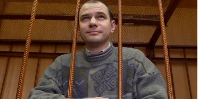 FILE: Russian arms control researcher Igor Sutyagin stands behind bars as he's sentenced to 15 years in prison for spying on April 7, 2004 in a Moscow courtroom.