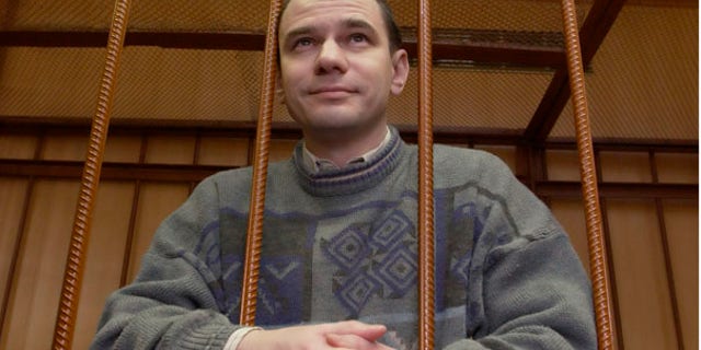 FILE: Russian arms control researcher Igor Sutyagin stands behind bars as he's sentenced to 15 years in prison for spying on April 7, 2004 in a Moscow courtroom.
