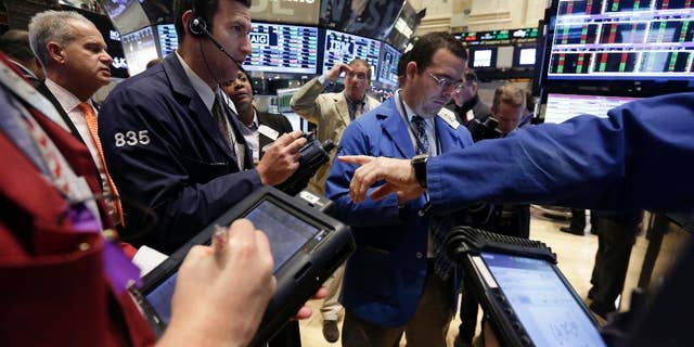 Traders gather at a post on the floor of the New York Stock Exchange Tuesday, Jan. 6, 2015. The U.S. stock market is edging higher in early trading as the price of oil extends its slump. (AP Photo/Richard Drew)
