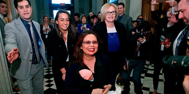 Sen. Tammy Duckworth, D-Ill., carries her baby Maile Pearl Bowlsbey as she heads to the Senate floor to vote, with Sen. Claire McCaskill, D-Mo., at right, on Capitol Hill, Thursday, April 19, 2018 in Washington. (AP Photo/Alex Brandon)