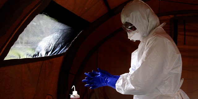 FILE - In this Sept. 24, 201, file photo, nurse Dalila Martinez, trainer of the Cuban medical team to travel to Sierra Leone, washes her gloved hands during a practice drill at a training camp, in Havana, Cuba. Cuba's health ministry is sending more than 160 health workers to help stop the raging Ebola outbreak in Sierra Leone in early October. Cuba says a member of the 165-member medical team it sent to fight Ebola in Sierra Leone has been diagnosed with the disease. (AP Photo/Ladyrene Perez, Cubadebate,File)