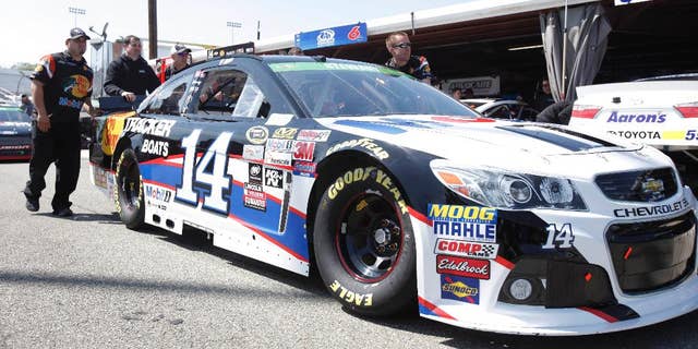 The pit crew for NASCAR Sprint Cup Series driver Tony Stewart (14) push his car to the inspection station at Richmond International Raceway in Richmond, Va., Friday, April 24, 2015. (AP Photo/Scott P. Yates)