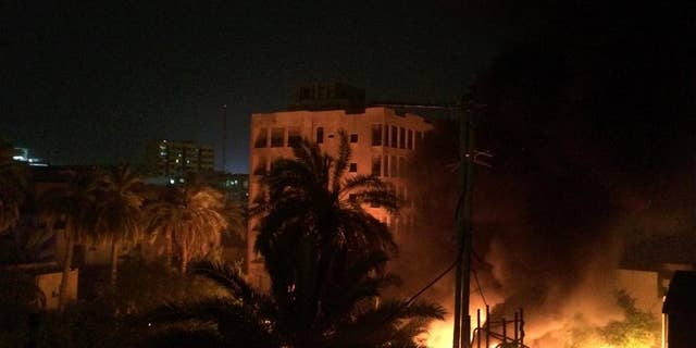 A fire erupts as smoke billows from the site of a car bomb, Friday, April 28, 2017, in Baghdad. Iraqi police and hospital officials said a car bomb at a police station in central Baghdad killed four and wounded eight late Friday night. The attack comes as Iraqi forces struggle to push back Islamic State group militants in the northern Iraqi city of Mosul, the last pocket of major urban territory the group holds in Iraq. (AP Photo/Susannah George)
