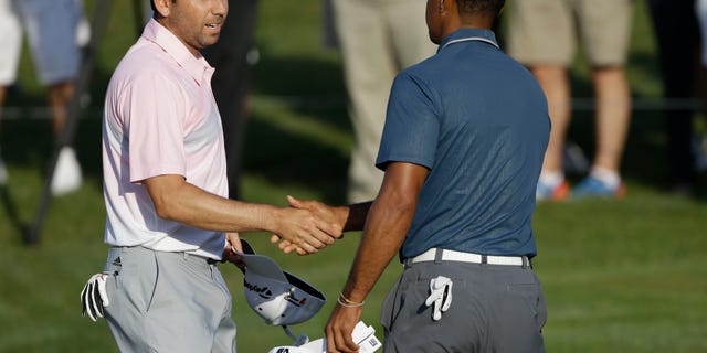 In this photo made May 12, 2013, Sergio Garcia, of Spain, left, shakes hands with Tiger Woods at the end of the third round of The Players championship golf tournament at TPC Sawgrass in Ponte Vedra Beach, Fla. Garcia apologized to Woods on Wednesday, May 22, 3013, for saying he would have "fried chicken" at dinner with his rival, a comment that Woods described as hurtful and inappropriate. (AP Photo/Gerald Herbert)