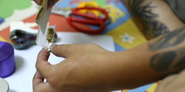 In this Oct. 1, 2013 photo, a man rolls a joint with Canadian-grown marijuana at his room in the old quarter area of Hanoi, Vietnam. Western-grown marijuana is available in Vietnam and popular among its elite, a result of its passion for imported products and the widespread involvement of Vietnamese diaspora gangs in the cultivation of marijuana in North America and Europe. (AP Photo/Na Son Nguyen).