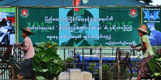 Myanmar women push their bicycles in the foreground of governing Union Solidarity and Development Party (USDP) office in capital Naypyitaw, Myanmar, Thursday, Sept. 17, 2015. Myanmar’s general elections are scheduled for November 8, 2015, the first since a nominally civilian government was installed in 2011. (AP Photo/Aung Shine Oo)