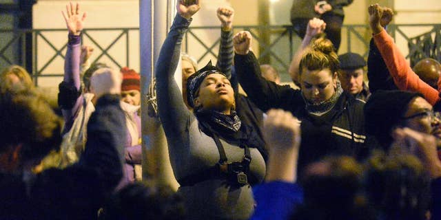 Protesters hold a moment of silence for Keith Lamont Scott in front of Charlotte-Mecklenburg Police Department headquarters, in the aftermath of no indictment being given in the death of Keith Lamont Scott, in Charlotte, N.C., Wednesday, Nov. 30, 2016. A prosecutor has cleared a Charlotte police officer in the killing of a black man whose death touched off civil unrest, and he presented detailed evidence to rebut assertions that the slain man was unarmed. Charlotte-Mecklenburg District Attorney Andrew Murray said Wednesday that Officer Brentley Vinson was justified in opening fire on Scott and won't face charges. (David T. Foster III/The Charlotte Observer via AP)