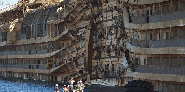 Workers from US salvage company Titan and Italian firm Micoperi inspect the wreck of the Costa Concordia cruise ship after it was hauled out of the water, in Giglio harbour on September 18, 2013