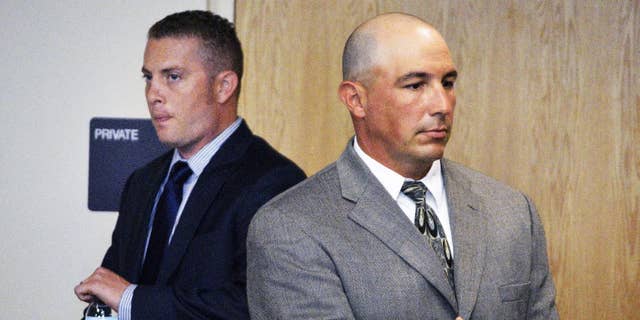Former Albuquerque Detective Keith Sandy, center, listens to a special prosecutor tell a judge at a preliminary hearing that he unlawfully shot a homeless camper who posed no threat in Albuquerque, N.M. on Monday, Aug. 3, 2015. Sandy and Albuquerque officer Dominique Perez are facing second-degree murder charges in the 2014 fatal shooting death of 38-year-old James Boyd. (AP Photo/Russell Contreras)