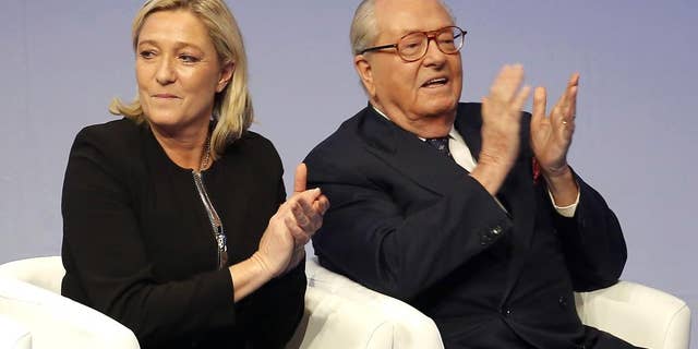 FILE - In this Saturday Nov. 29, 2014 file photo, French far-right Front National leader Marine Le Pen and her father Jean-Marie Le Pen applaud in Lyon, central France. A French court has reinstated Thursday July 2, 2015 Jean-Marie Le Pen as a member of the far right National Front party he founded decades ago, sending a biting blow to his daughter and party president Marine Le Pen, who had suspended him after a series of controversial and anti-Semitic statements. (AP Photo/Laurent Cipriani, File)