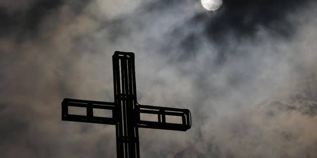 Dark clouds partially cover the sun above a church on Easter Sunday April 5, 2015 in suburban Quezon city, north of Manila, Philippines.  Tropical storm Maysak weakened before hitting the Philippines' northeastern coast Sunday, driving away thousands of Lenten holiday vacationers and tourists. (AP Photo/Aaron Favila)