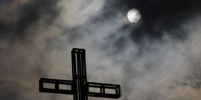 Dark clouds partially cover the sun above a church on Easter Sunday April 5, 2015 in suburban Quezon city, north of Manila, Philippines. Tropical storm Maysak weakened before hitting the Philippines' northeastern coast Sunday, driving away thousands of Lenten holiday vacationers and tourists. (AP Photo/Aaron Favila)