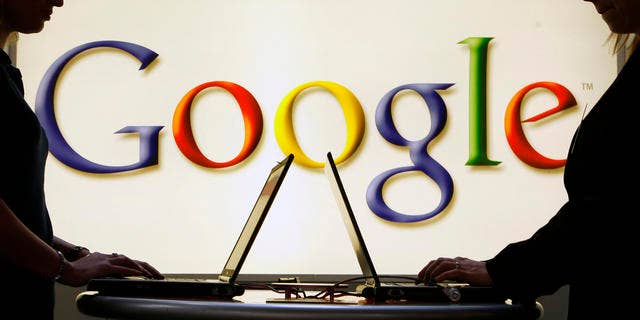 FILE: Exhibitors of the Google company work on laptop computers in front of an illuminated sign of the Google logo at the industrial fair Hannover Messe in Hanover, Germany.