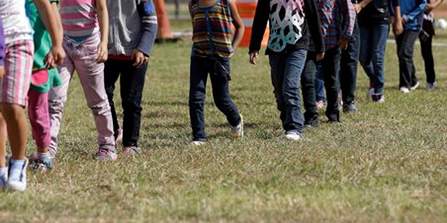 Detainees walk in a line at a U.S. Customs and Border Protection processing facility, June 18, 2014, in Brownsville,Texas.