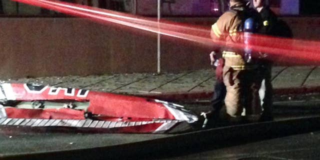 Firefighters stand near a piece of wreckage after a small plane slammed into a commercial building in downtown Anchorage, Alaska, early Tuesday, Dec. 29, 2015. Authorities say at least one person aboard died. Assistant Fire Chief Alex Boyd said there were no injuries on the ground.(AP Photo/Rachel D'Oro)