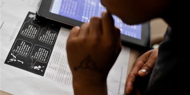 In this photo taken Sept. 11, 2014, a student in the Accelerating Preliterate English Language Learners (A.P.E.L.L) class, taught by Lori Ott, of Millsboro, Del., at the G.W. Career Educational Center in Frankford, Del., looks over a worksheet aimed at teaching basic introductions in English. U.S. schools are now dealing with the fallout from the dramatic spike in the number of children and teenagers who crossed into the United States unaccompanied by family; the Supreme Court has ruled that they have an obligation to educate all students regardless of their immigration status. (AP Photo/Emily Varisco)