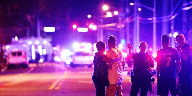 2016 AP YEAR END PHOTOS - Orlando Police officers direct family members away from a fatal shooting at Pulse nightclub in Orlando, Fla., on June 12, 2016. Omar Mateen, a 29-year-old security guard, killed 49 people and wounded 53 others in the mass shooting. (AP Photo/Phelan M. Ebenhack, File)
