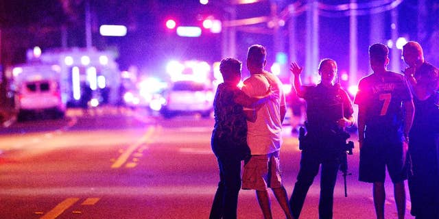 2016 AP YEAR END PHOTOS - Orlando Police officers direct family members away from a fatal shooting at Pulse nightclub in Orlando, Fla., on June 12, 2016. Omar Mateen, a 29-year-old security guard, killed 49 people and wounded 53 others in the mass shooting. (AP Photo/Phelan M. Ebenhack, File)