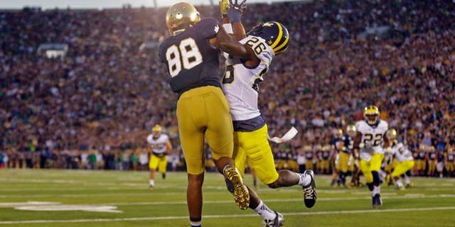 Michigan defensive back Jourdan Lewis, right, interferes with Notre Dame wide receiver Corey Robinson in as he attempts a catch in the end zone during the first half of an NCAA college football game in South Bend, Ind., Saturday, Sept. 6, 2014. (AP Photo/Michael Conroy)