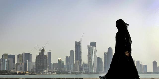 In this May 14, 2010 file photo, a Qatari woman walks in front of the city skyline in Doha, Qatar.