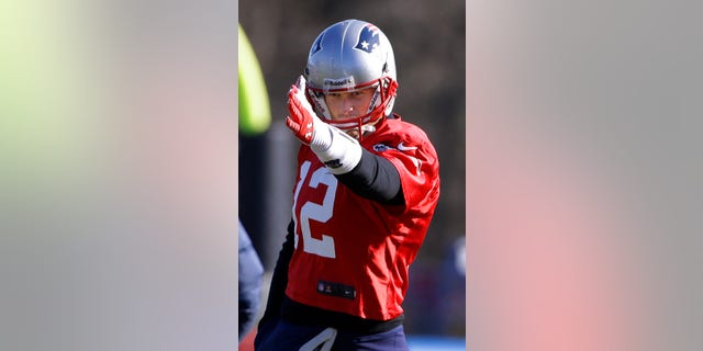 New England Patriots quarterback Tom Brady (12) gestures the direction of a route he wants run during a stretching and drills session before practice begins at the NFL football team's facility in Foxborough, Mass., Wednesday, Nov. 20, 2013. Tom Brady and the Patriots will play Peyton Manning and the Denver Broncos Sunday night in Foxborough. (AP Photo/Stephan Savoia)