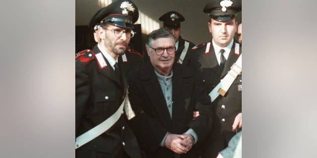 Mafia ″boss of bosses″ Salvatore ″Toto″ Riina, center, enters handcuffed into Bologna’s bunker-courtroom, escorted by Carabinieri, Italian paramiliary police, in Bologna, Italy, in January 1996.
