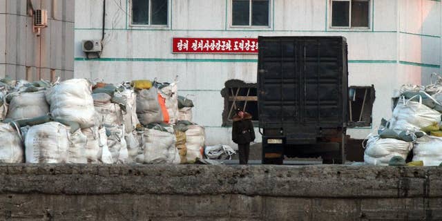 a North Korean soldier walks past a truck park near the goods pile up on a dockyard in Sinuiju, North Korea, as seen from Dandong in northeastern China's Liaoning province.