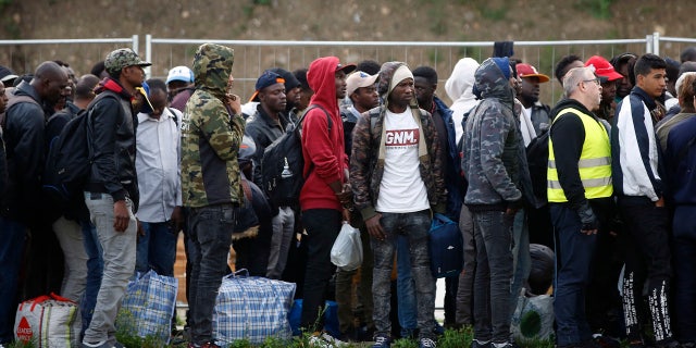 May 30: Migrants line up in a makeshift camp during its evacuation, in Paris. Authorities moved in on the so-called Millennaire tent camp on the city's edge alongside a canal used by joggers and cyclists.