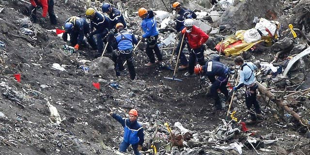 FILE - In this Thursday March 26, 2015 file photo, rescue workers inspect the debris from the Germanwings jet at the crash site near Seyne-les-Alpes, France. The somber mission to recover the remains of 150 people killed instantly when the Germanwings flight crashed full speed into the Col de Mariaud is not a quiet one and crucial physical evidence for the crash investigation can be gathered only when the mountains cooperate. (AP Photo/Laurent Cipriani, File)