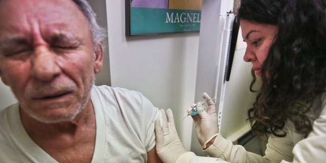 FILE -Carlos Maisonet, 73, reacts as Dr. Eva Berrios-Colon, a professor at Touro College of Pharmacy, injects him with flu vaccine during a visit to the faculty practice center at Brooklyn Hospital in New York.