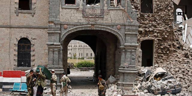 Shiite rebels known as Houthis wearing army uniforms stand guard in front of Yemen's Defense Ministry building after it was damaged by Saudi-led airstrikes in Sanaa, Yemen, Wednesday, June 10, 2015. A series of airstrikes by the Saudi-led military coalition on Tuesday struck the building, which is under the control of Shiite rebels who last year seized the capital, Sanaa, officials said. (AP Photo/Hani Mohammed)