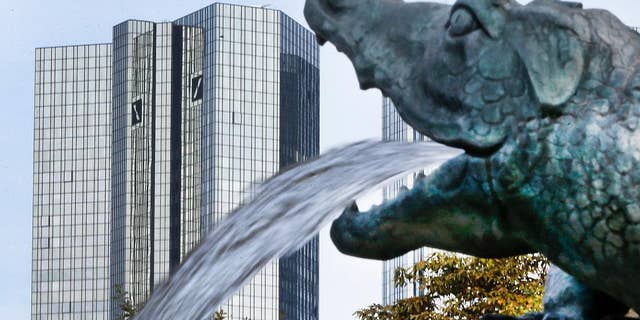 FILE - In this Oct. 11, 2016 file photo water spills out of a small dragon sculpture on a fountain with the headquarters of the Deutsche Bank in background in Frankfurt, Germany. The management board said in a message to employees Wednesday, Jan. 18, 2017 that vice presidents, directors and managing directors will receive group variable compensation but no individual bonuses for the financial year. (AP Photo/Michael Probst, file)