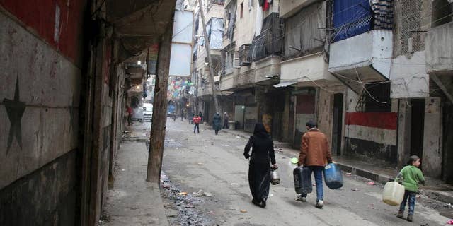 FILE -- In this February 11, 2016, file photo, civilians walk with containers for fuel and water in Aleppo, Syria. Dozens of State Department employees have endorsed an internal document that advocates U.S. military action to pressure Syria's government into accepting a ceasefire and engaging in peace talks, officials said Thursday. The position is at odds with U.S. policy. (Alexander Kots/Komsomolskaya Pravda via AP, File)
