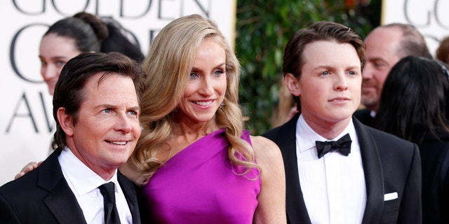 Actor Michael J. Fox, his wife Tracy Pollan and their son Sam Fox (R) arrive at the 70th annual Golden Globe Awards in Beverly Hills, California, January 13, 2013.